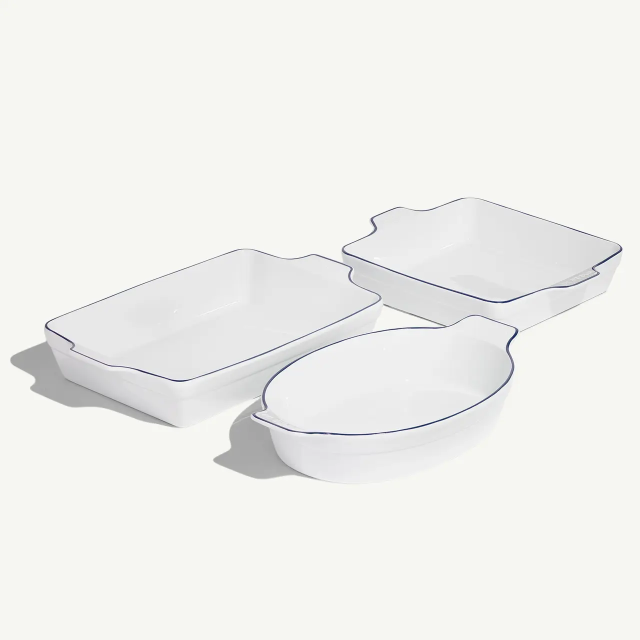 Three white ceramic baking dishes with scalloped edges are arranged on a light background.