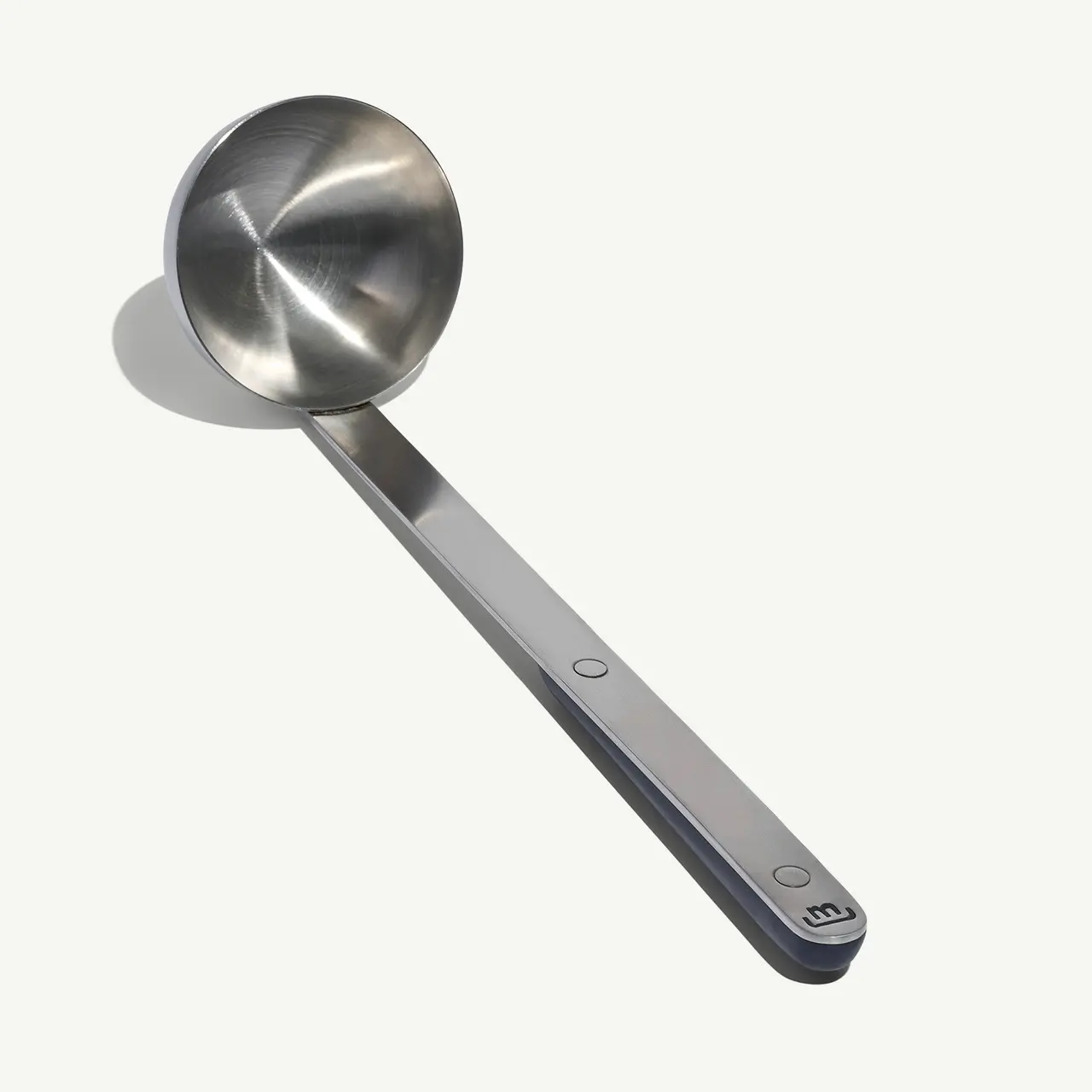 A stainless steel measuring spoon rests on a light background.