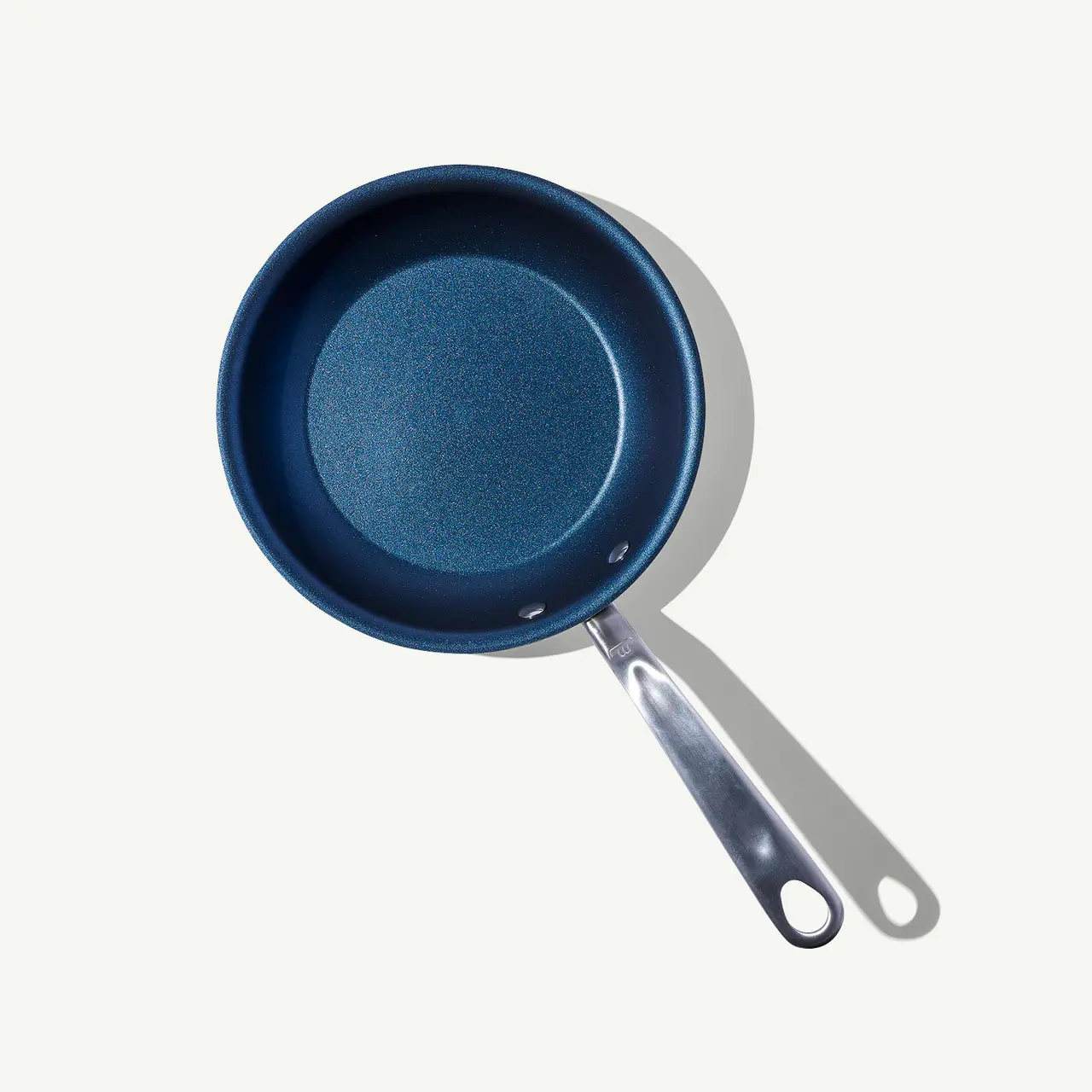 A non-stick frying pan with a blue interior and a silver handle lies against a light grey background.