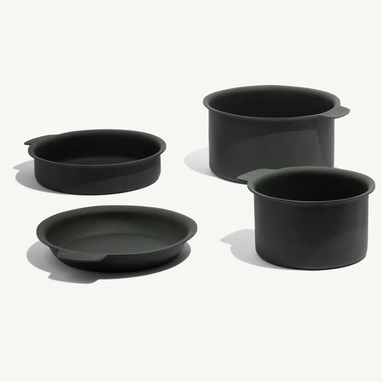 Four dark green kitchen pots and pans of various shapes and sizes arranged together.