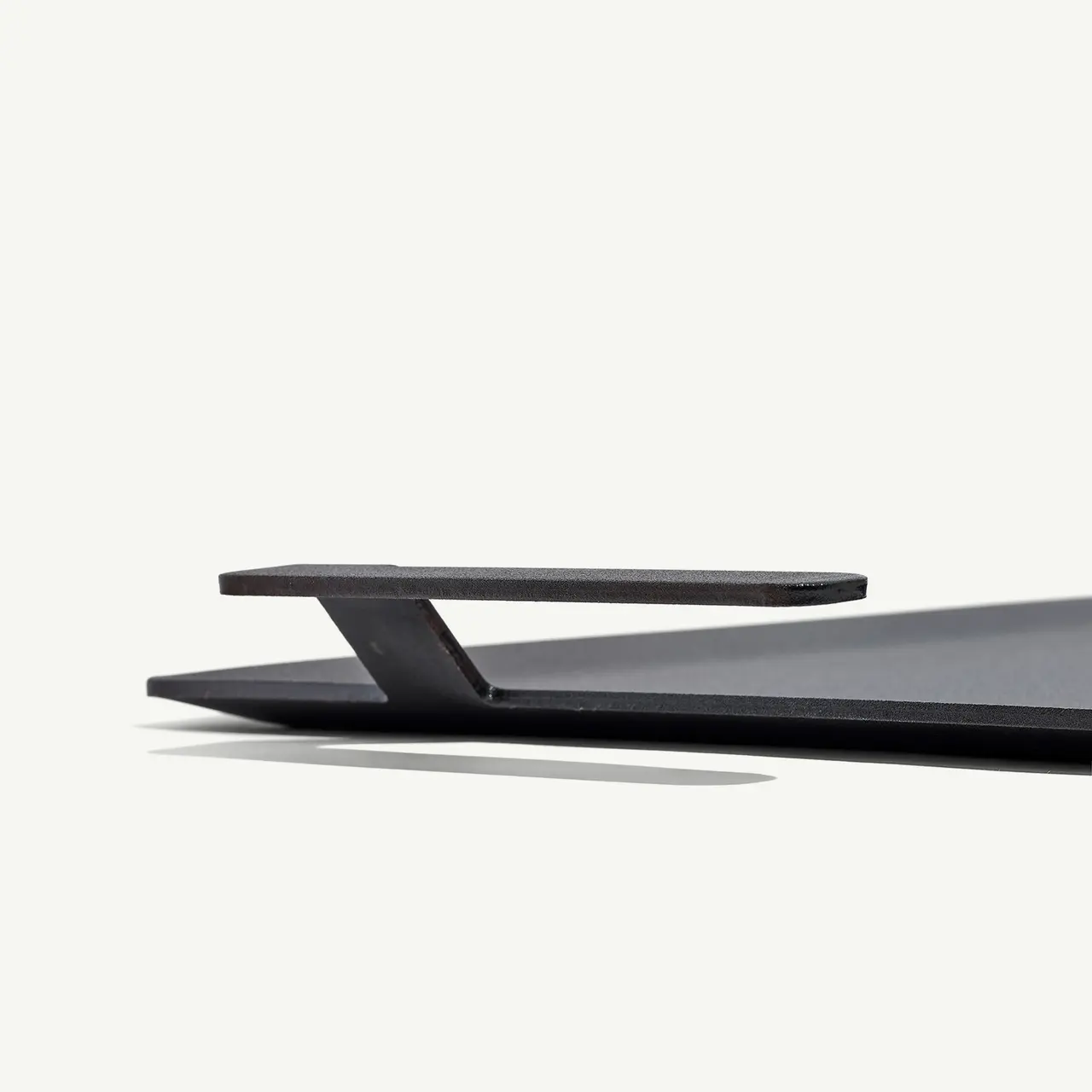 A sleek, minimalist black shelf is featured against a plain background, showcasing its thin design and subtle shadow.