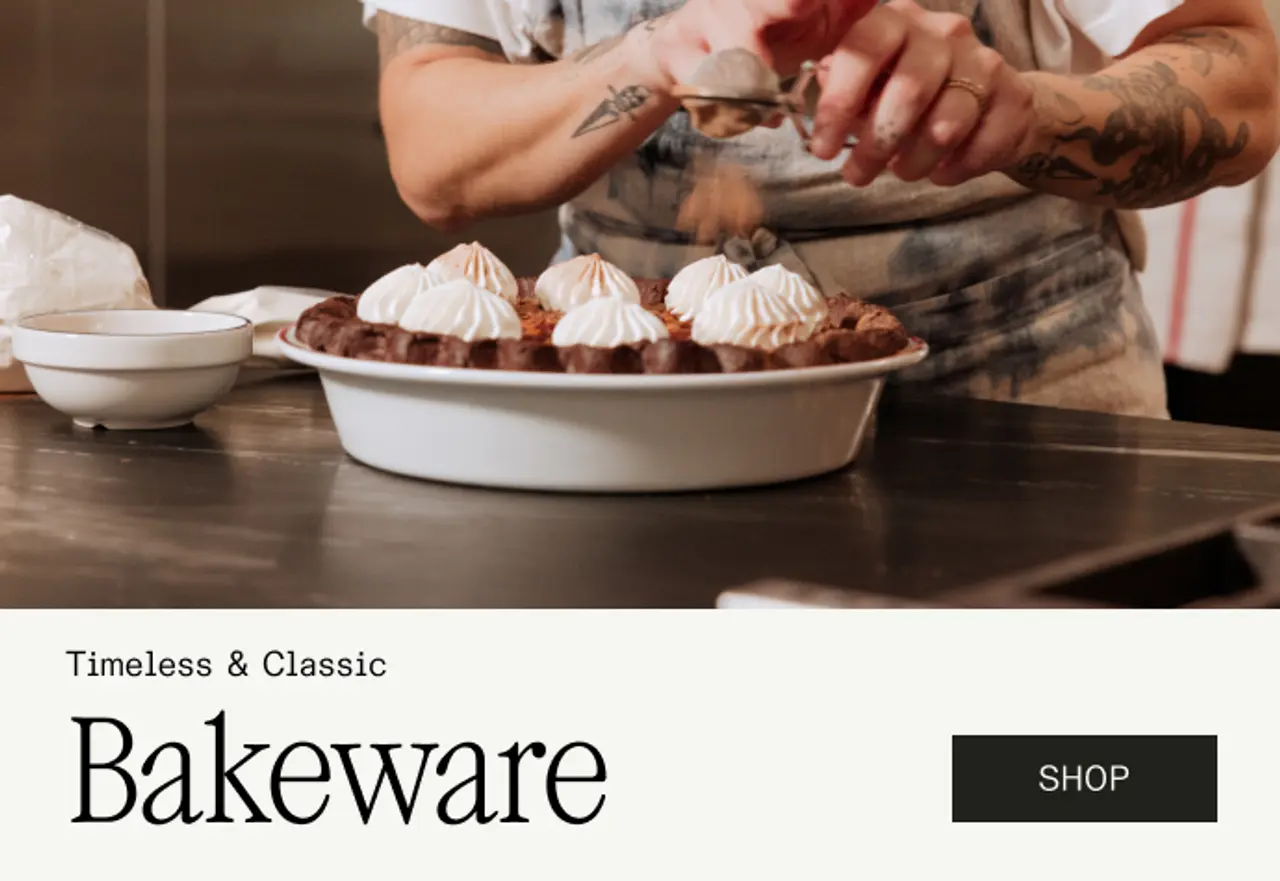 A person decorates a dessert with meringue while showcasing a bakeware set in an inviting kitchen setting.