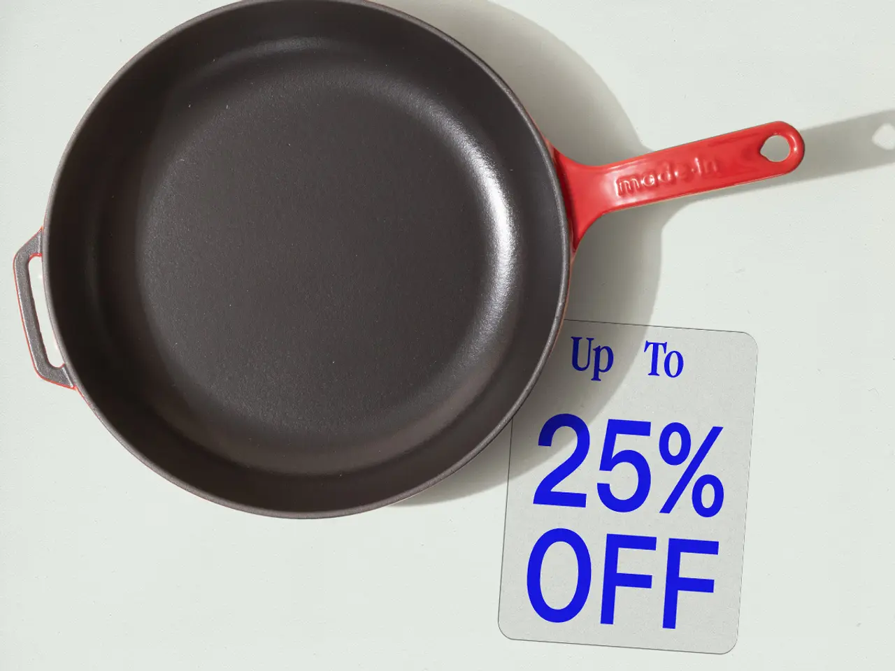 A red-handled frying pan is displayed next to a tag indicating a discount of up to 25% off.
