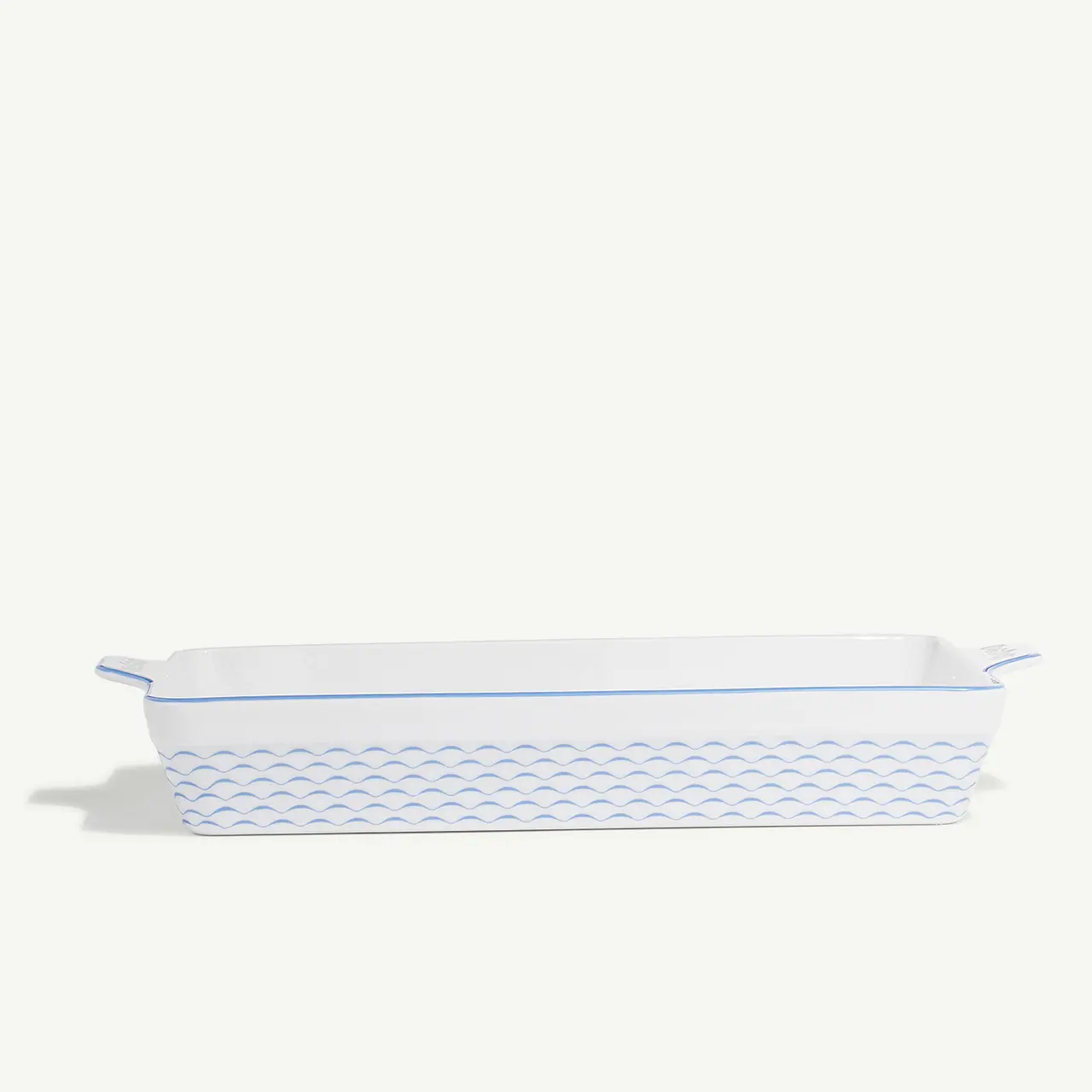 A white ceramic baking dish with blue trim and a fish scale pattern is displayed against a neutral background.