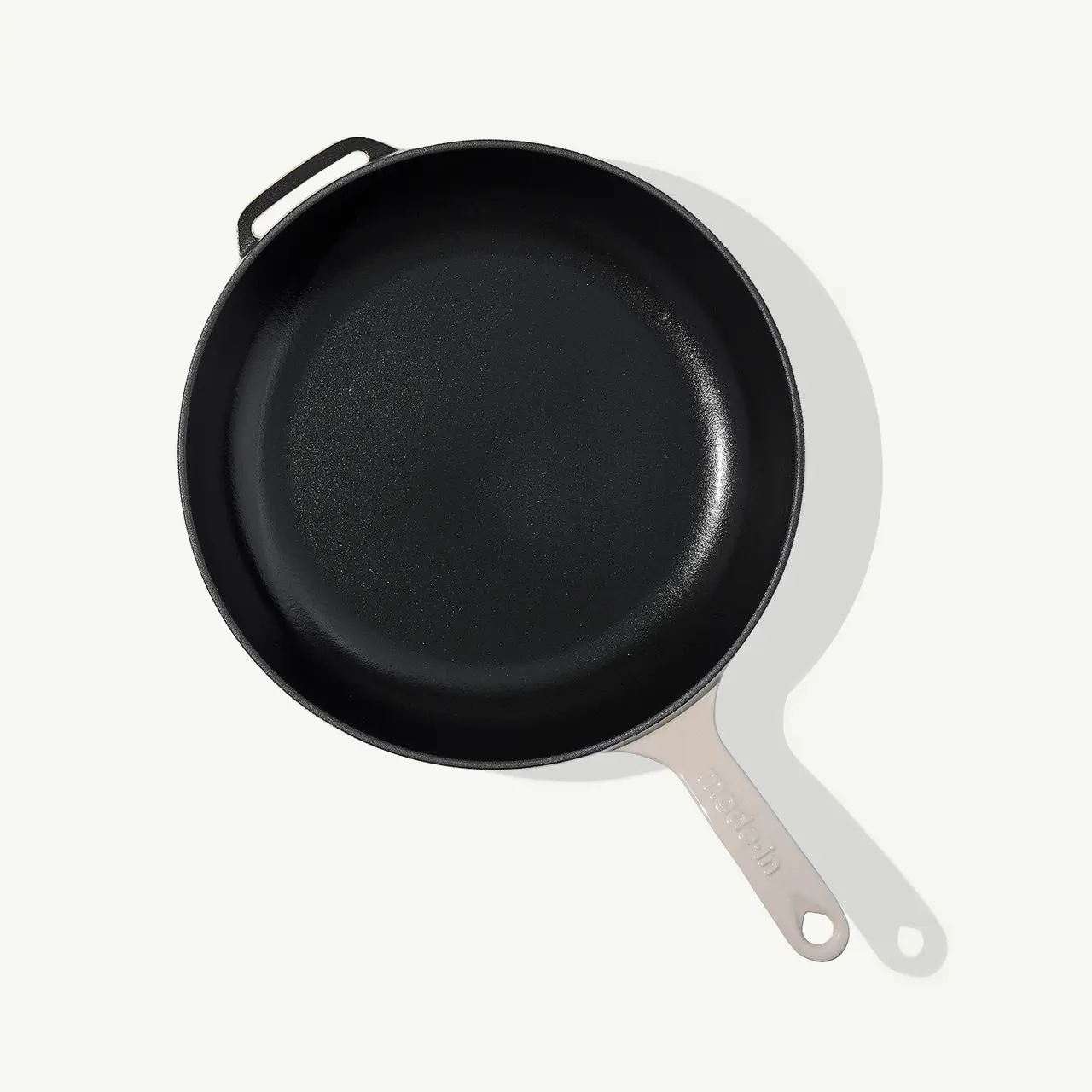 A cast iron skillet with a silver handle is shown from above on a light background.