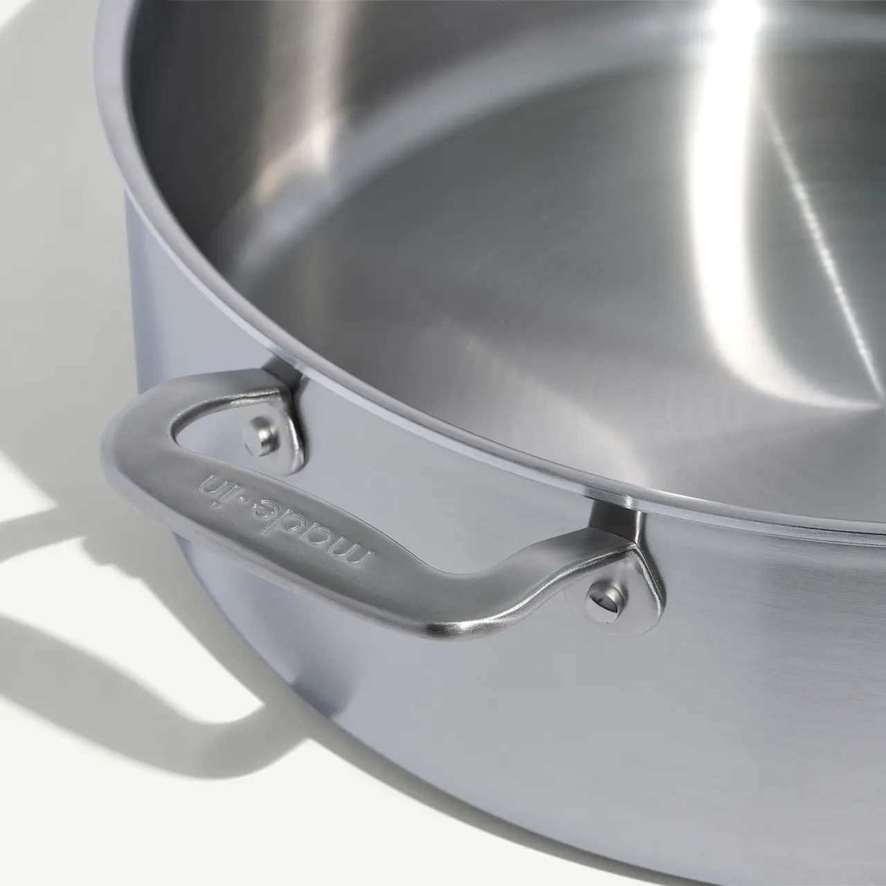 A close-up view of a stainless steel pot showcasing its shiny handle and reflective inner surface.