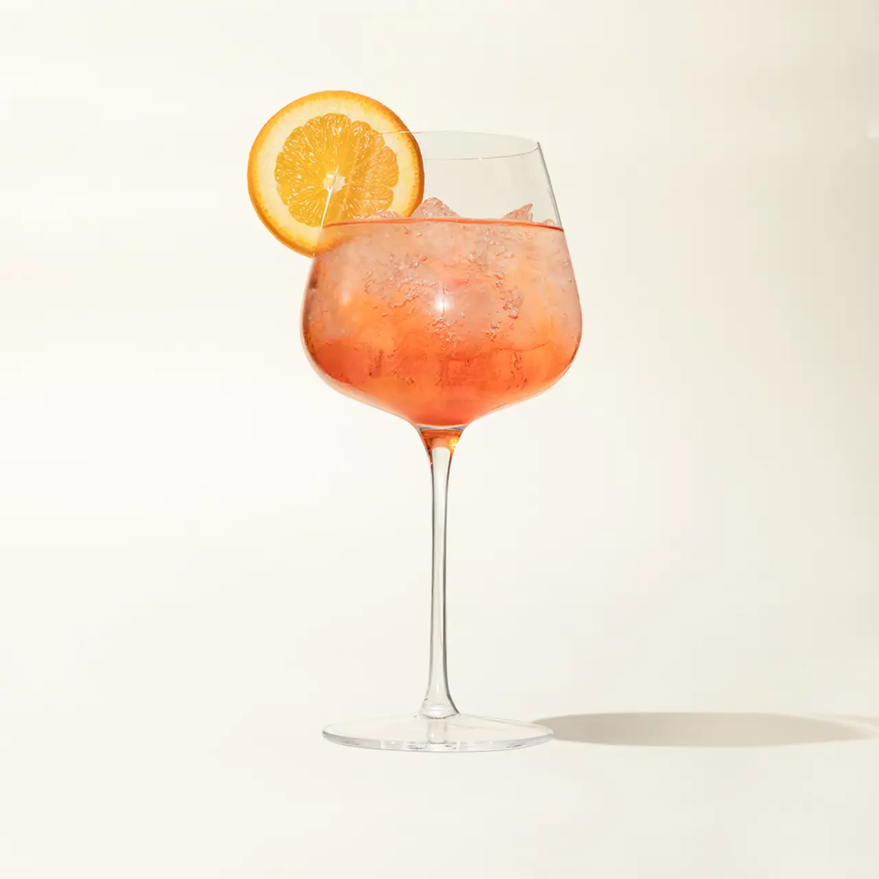 A refreshing cocktail with a slice of orange garnish is presented in a stemmed goblet.