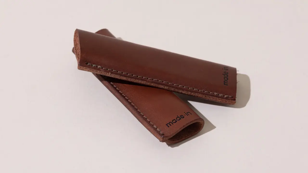 Two brown leather pen cases with stitched detailing, placed on a light background.