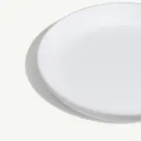 A simple white plate with a slightly curved edge, set against a light background.