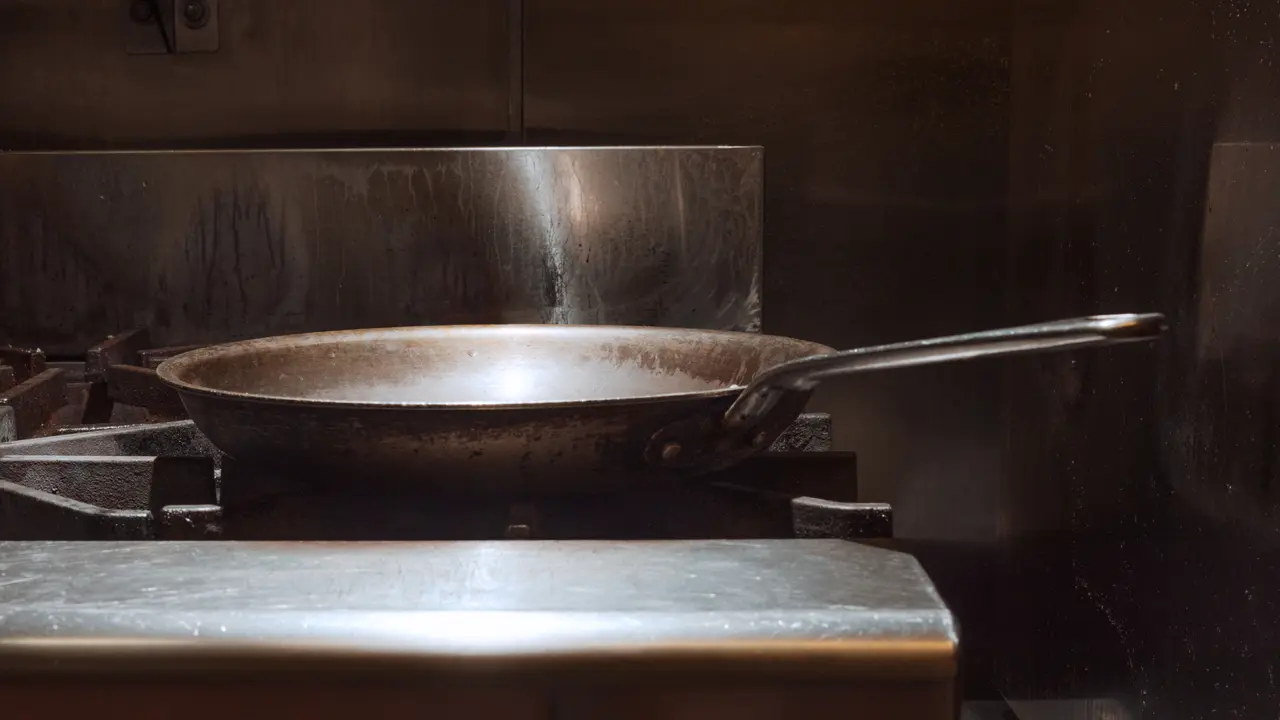 A well-used frying pan sits on a stovetop, hinting at recent cooking activity.
