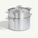 A stainless steel double boiler with a lid on a neutral background.