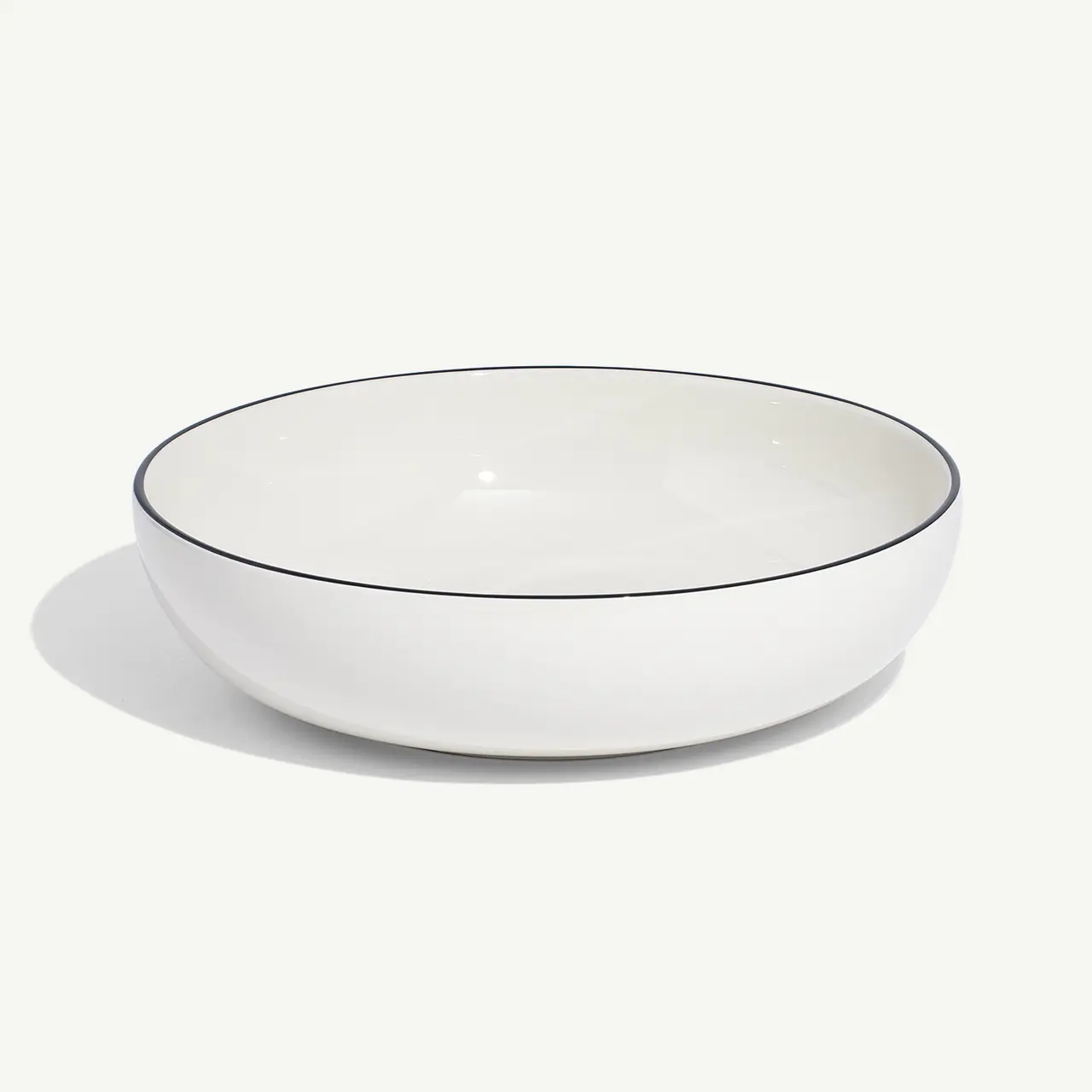 A simple white ceramic bowl with a subtle rim sits isolated on a plain background.