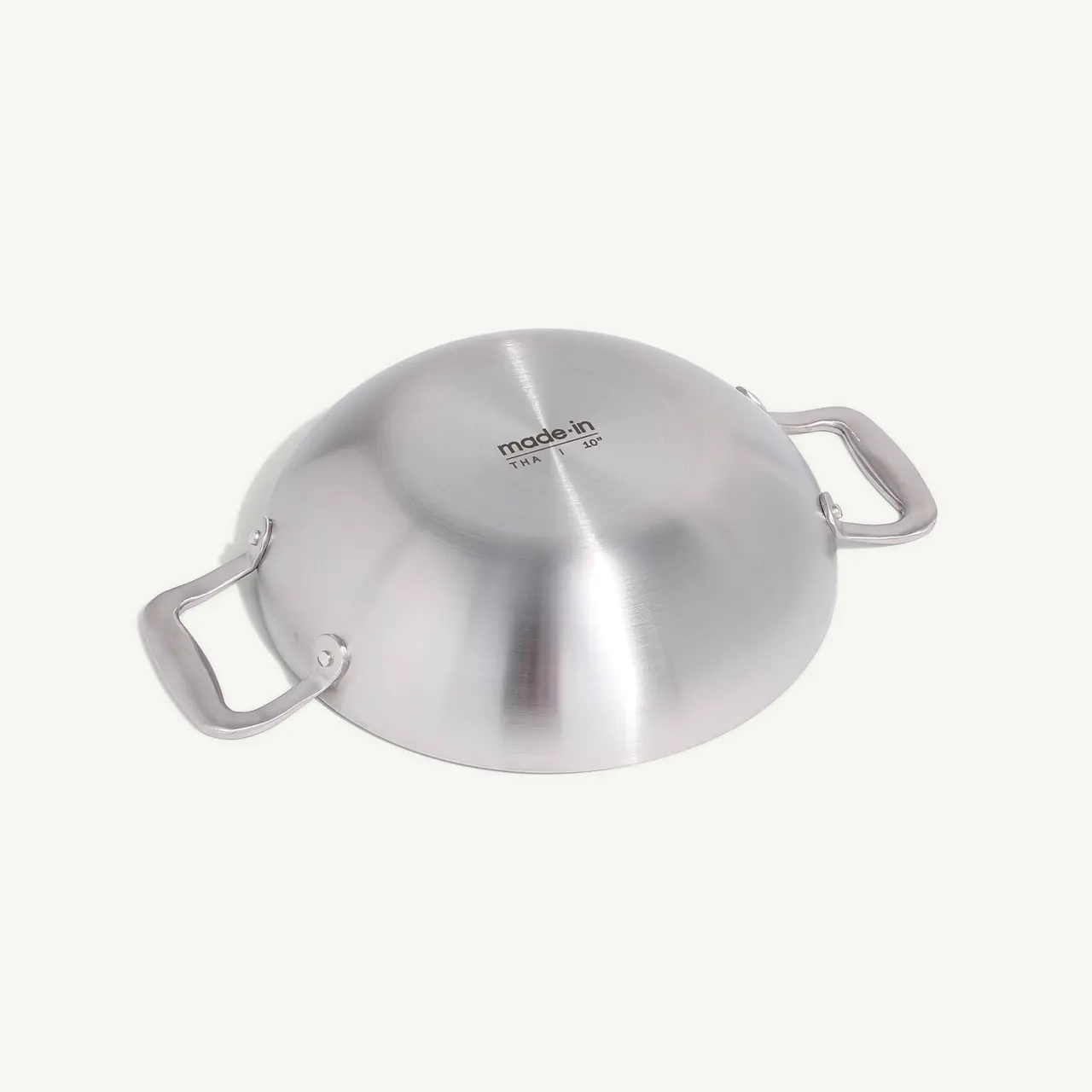 A stainless steel wok with two handles against a neutral background.