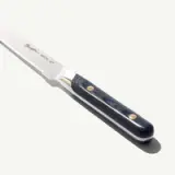 A serrated knife with a silver blade and a textured blue handle featuring two gold rivets.