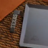 A metallic USB flash drive with the word "LEXIS" engraved on it rests beside a silver external hard drive on a textured surface.