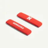 Two red hair clips featuring the word "NEBRASKA" and a large letter "N."