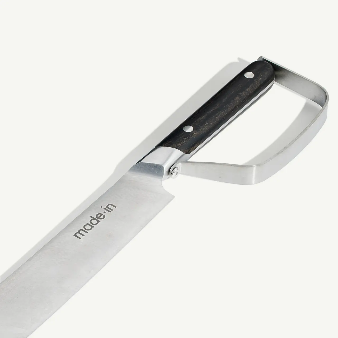 A close-up of a stainless steel kitchen knife with a black handle and the brand "made.in" engraved on the blade.