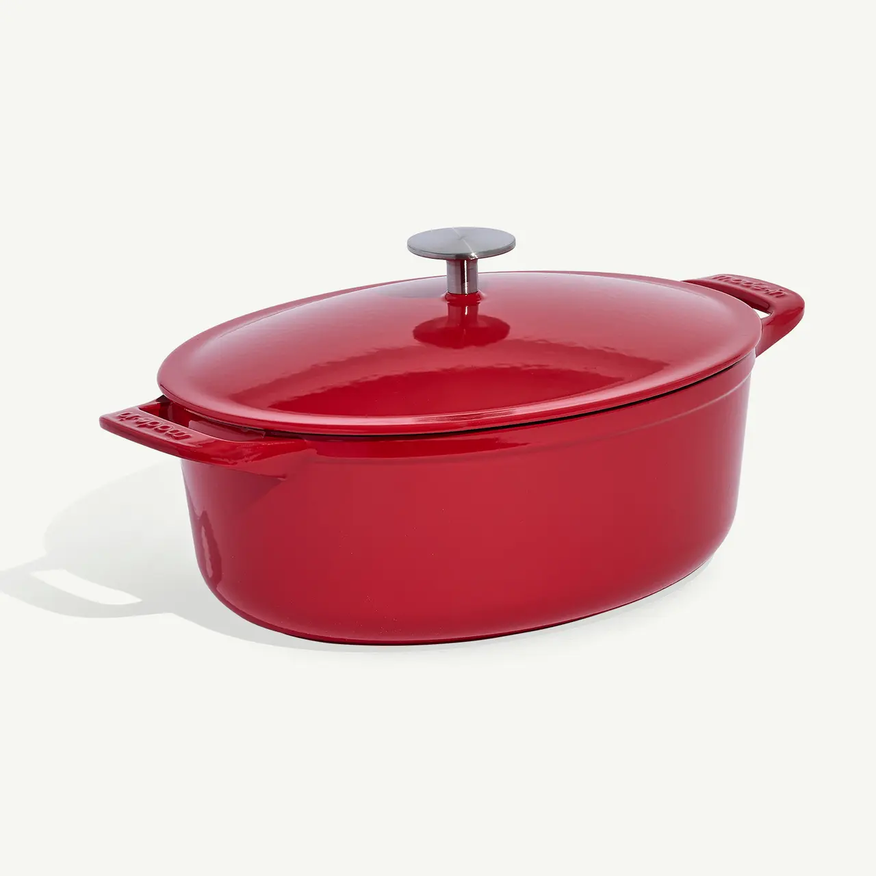 A red enameled cast iron dutch oven with a lid on a white background.