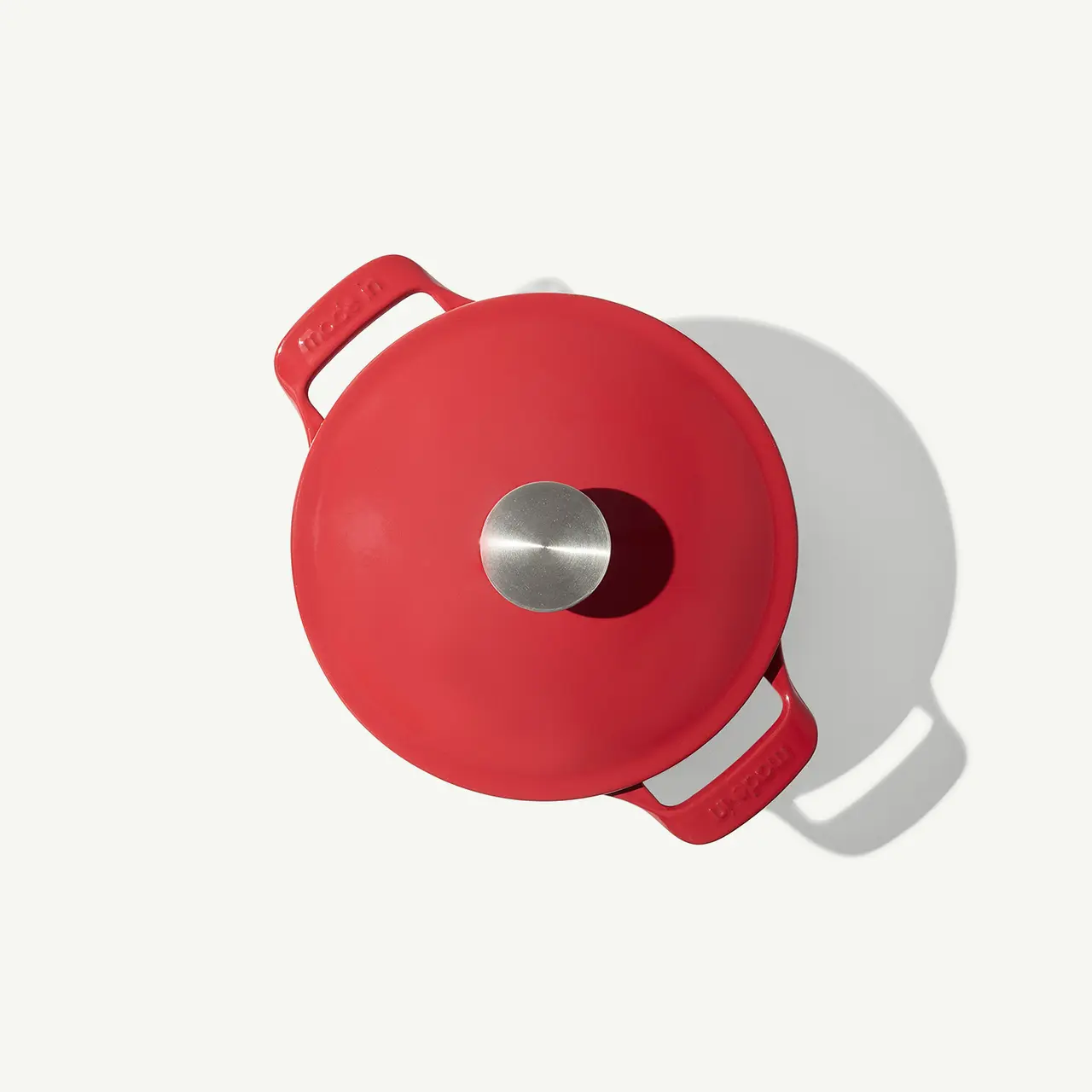 A red kettle with a silver spout and a lid handle is viewed from above against a white background.