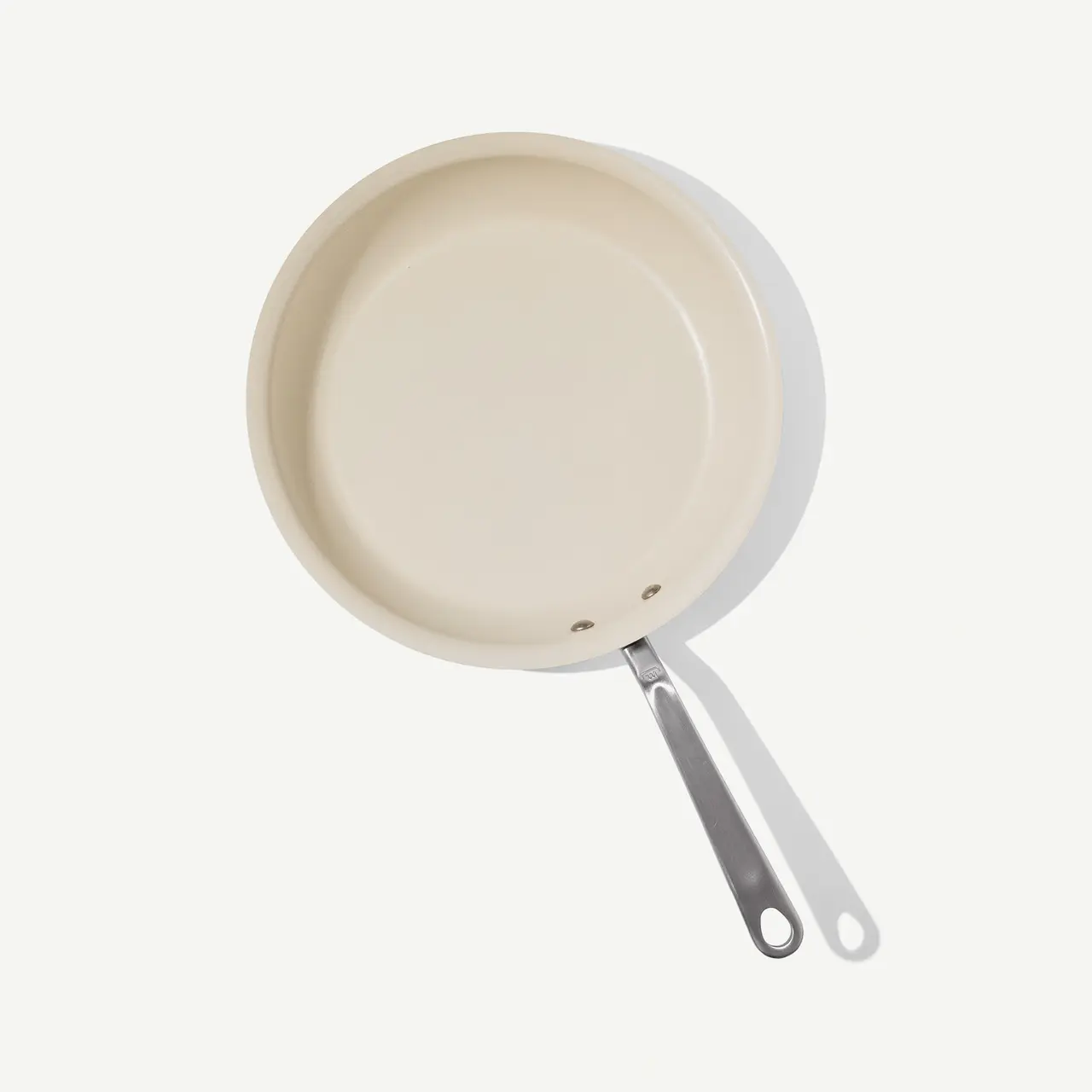 A beige-colored frying pan with a silver handle is displayed against a light background.