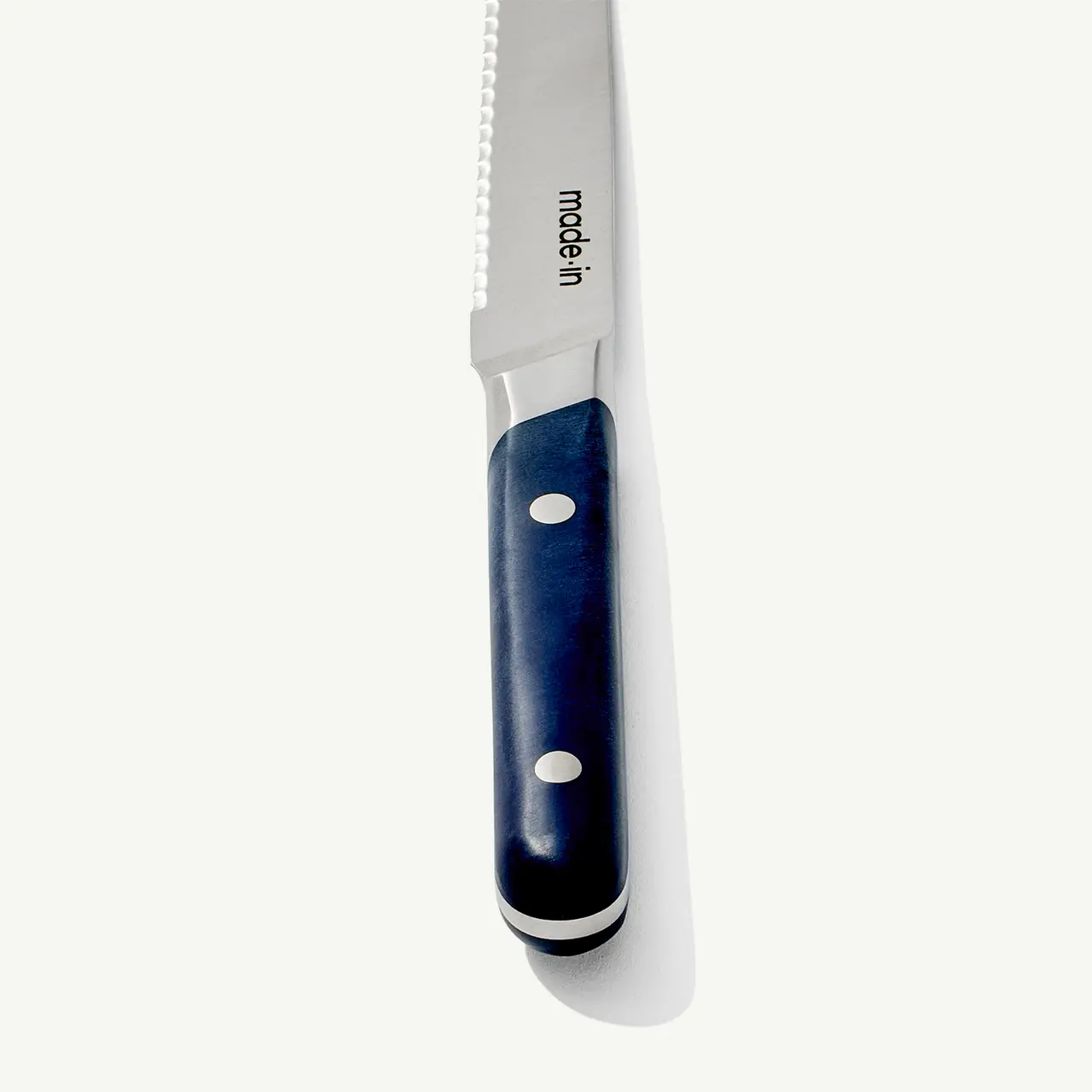 A close-up of a serrated bread knife with a dark blue handle against a white background.