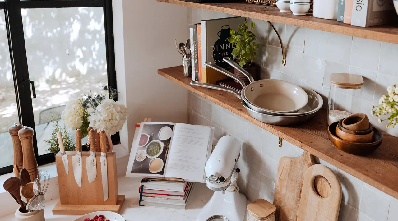 A well-organized kitchen shelf displays cooking books, a stand mixer, utensils, and various kitchenware, creating a cozy atmosphere.