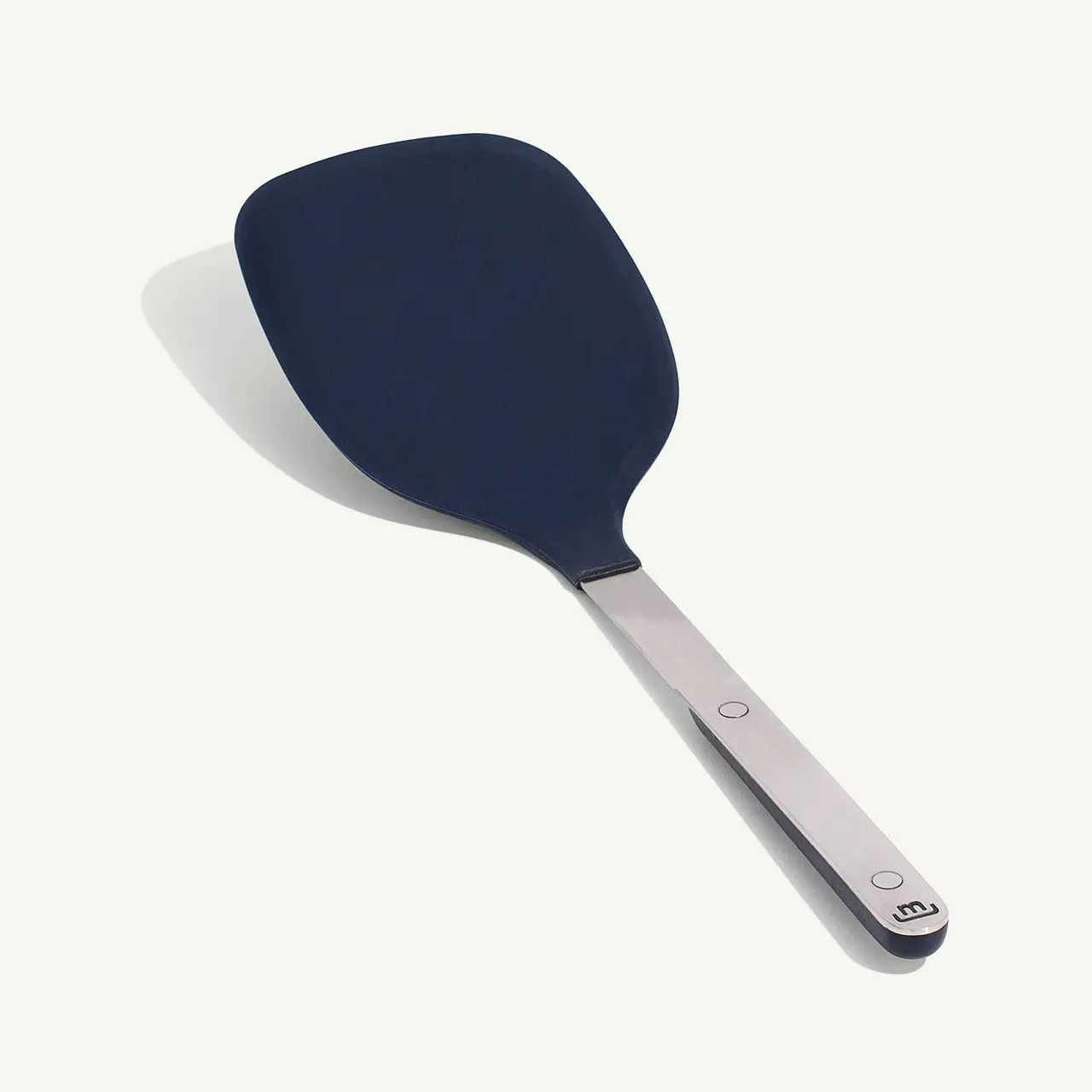 A blue silicone spatula with a stainless steel handle lies against a white background.