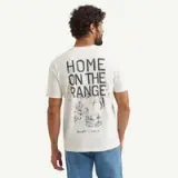 A man is wearing a light-colored t-shirt featuring the phrase "HOME ON THE RANGE" along with illustrations related to rural life on the back.