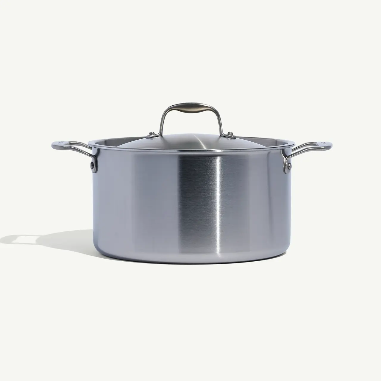 A stainless steel cooking pot with a lid on a plain background.