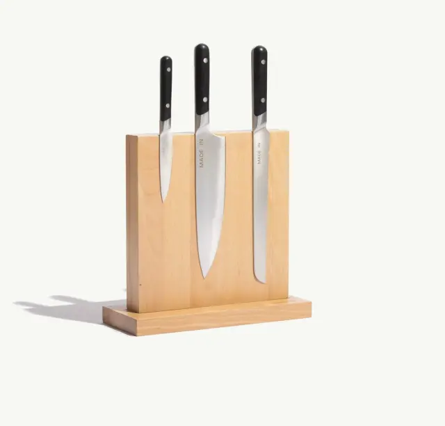 Three kitchen knives with black handles are displayed in a wooden knife block.