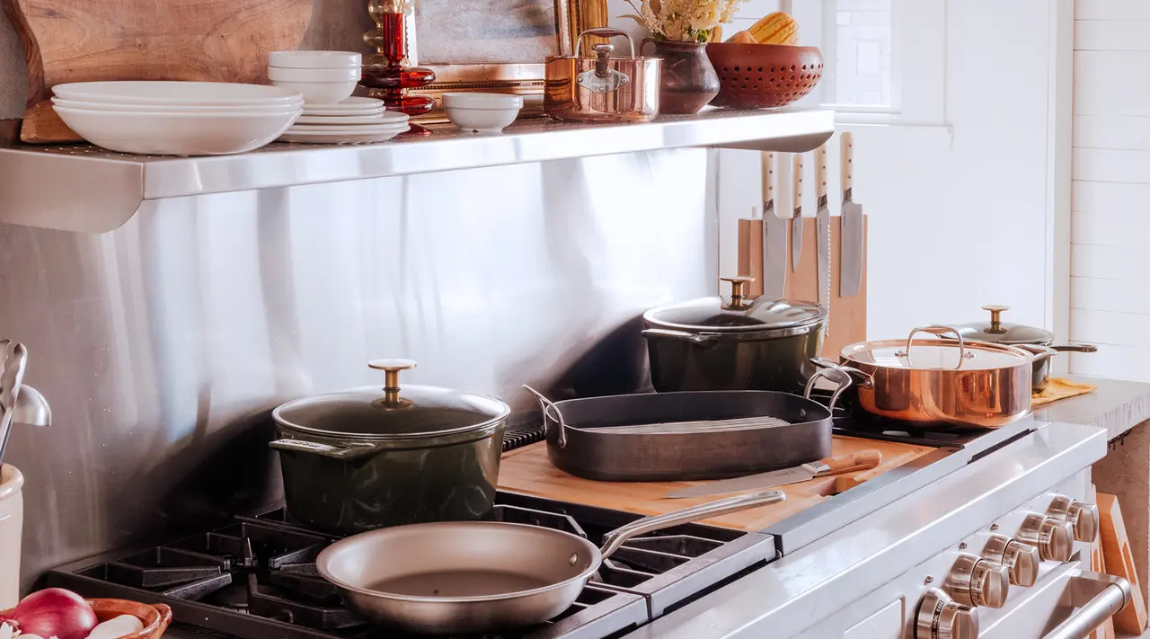 A well-organized kitchen counter is equipped with a stainless steel stove and an array of pots, pans, and utensils ready for cooking.
