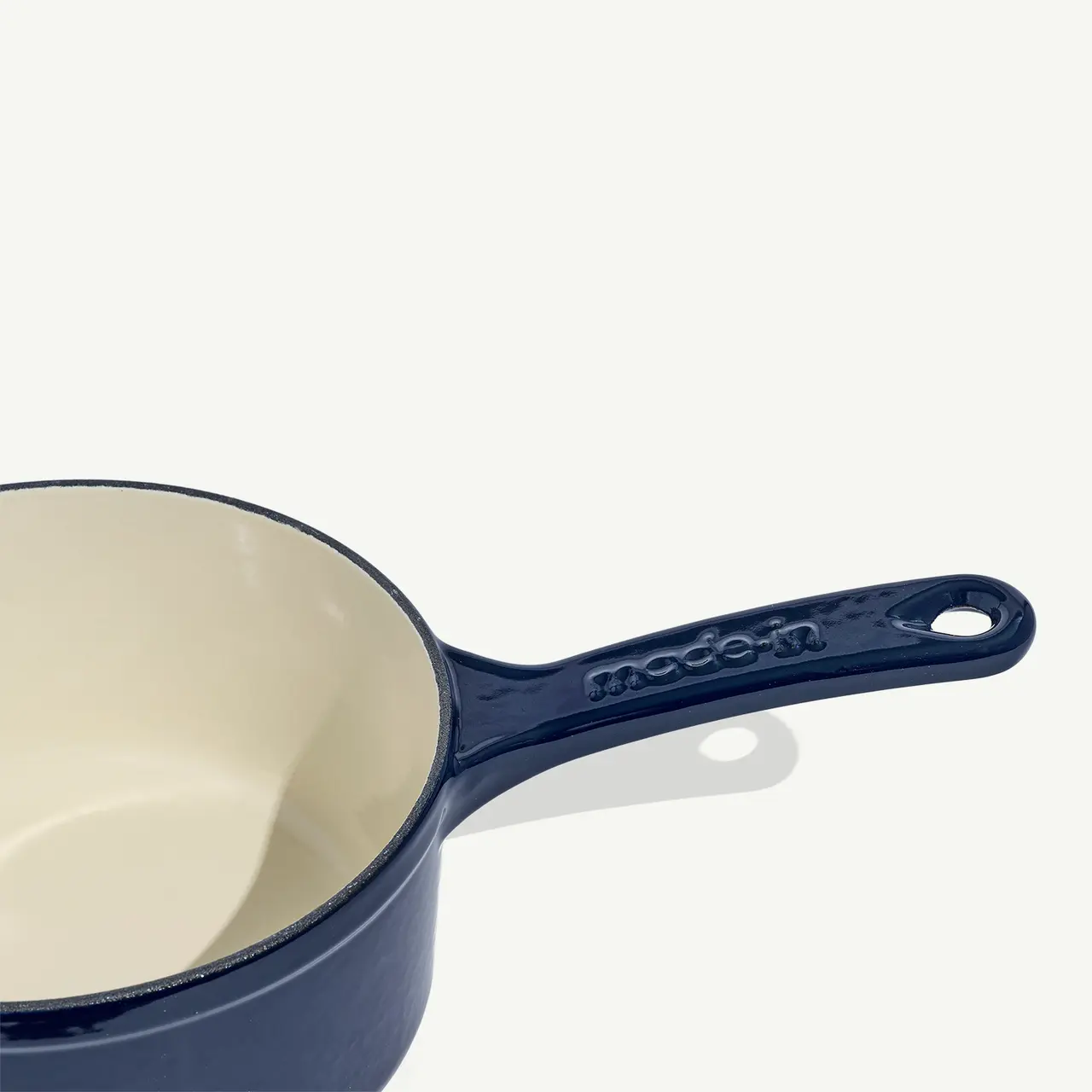 A blue ceramic saucepan with a cream interior and the word "modern" embossed on the handle sits against a light background.