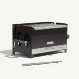 A sleek black toaster with a stainless steel front and a handle, accompanied by a metal tray for easy toast removal.