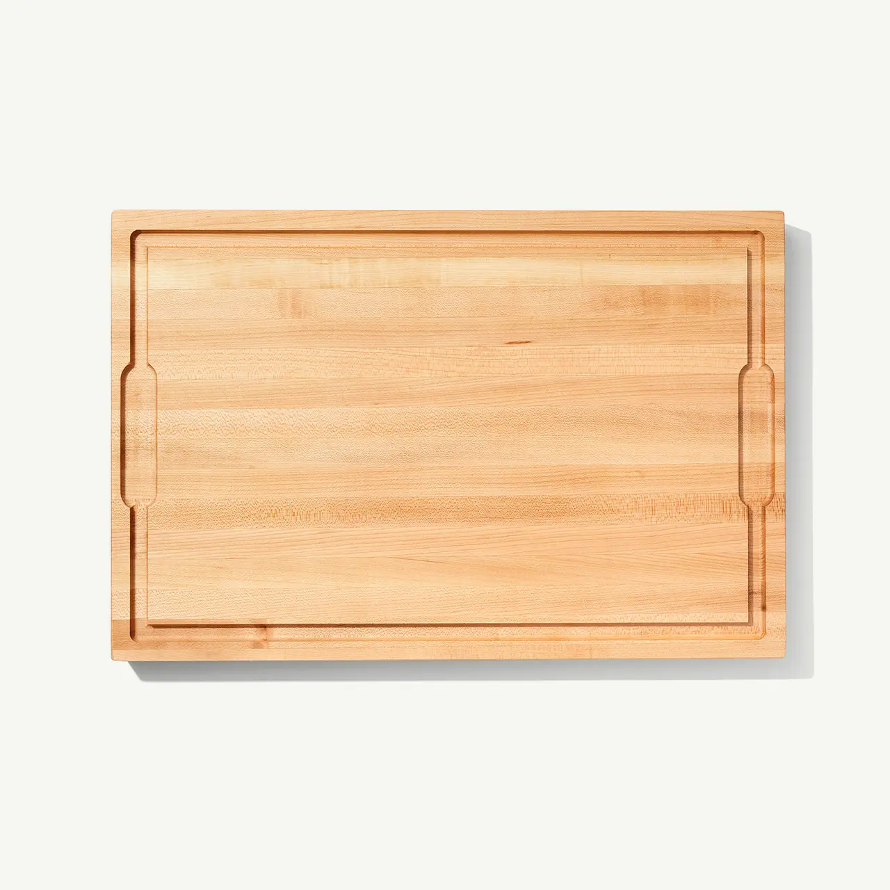 A simple, rectangular wooden cutting board with a visible grain and indented handles on the sides, presented on a plain white background.