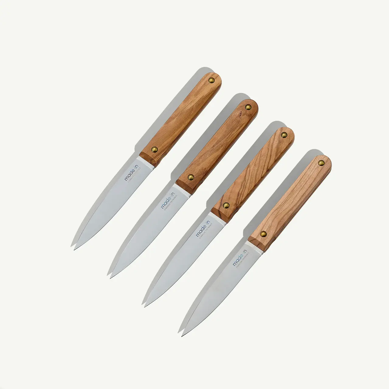 Four wooden-handled kitchen knives are aligned neatly against a light background.