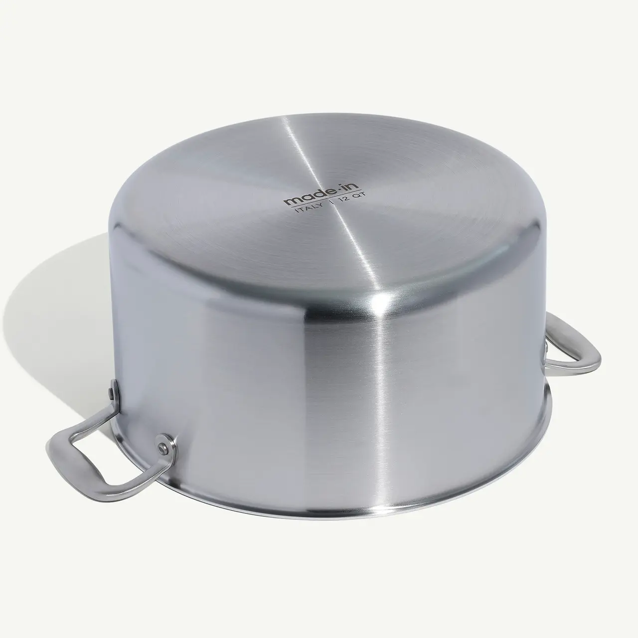 A stainless steel saucepan with handles and a lid sits against a white background.