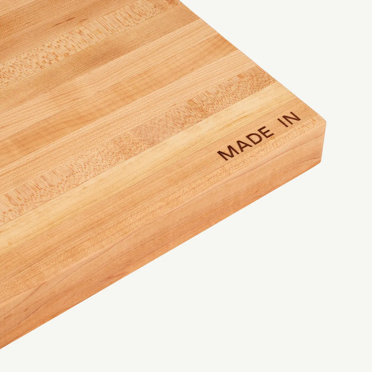 A wooden cutting board with the words "MADE IN" burned into the corner.