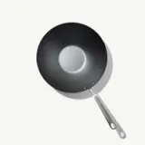 A round, black wok with a smooth interior and a stainless steel handle is shown against a light background.