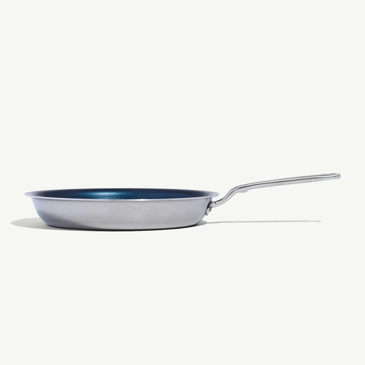 A stainless steel frying pan with a blue interior sits on a plain white background.