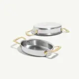 A sleek stainless steel cookware piece with golden handles, featuring both a shallow dish and a matching lid.