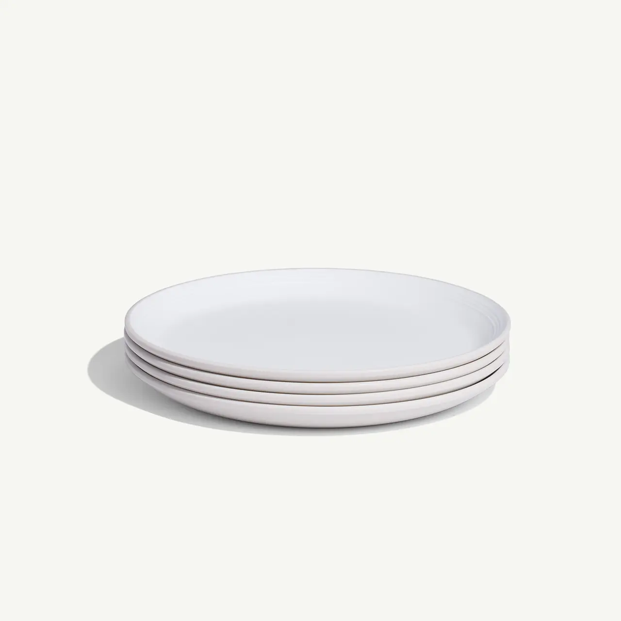 A stack of plain white plates is presented on a light background.