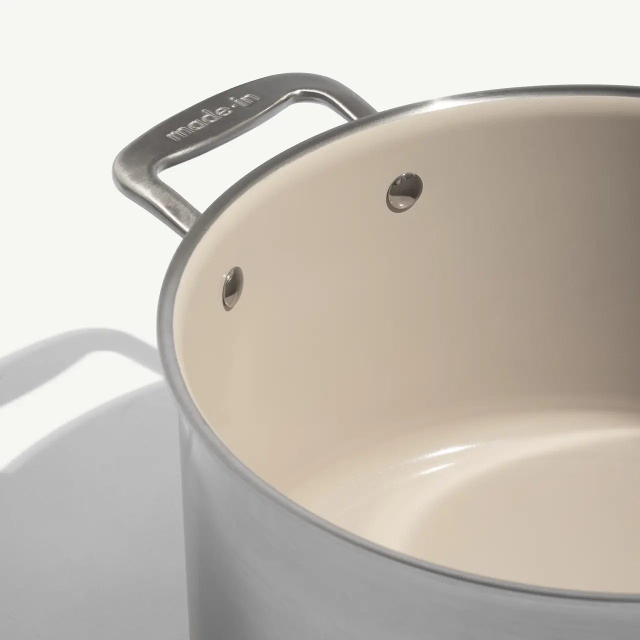 A stainless steel cooking pot with a smooth, light-colored interior and dual handles.