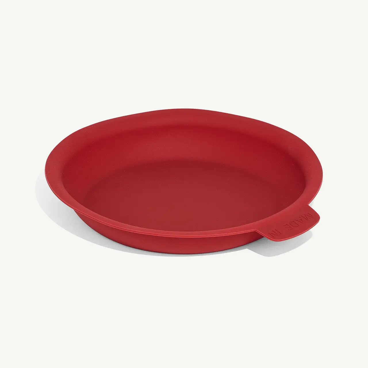 A red silicone baking mat lies on a white surface.