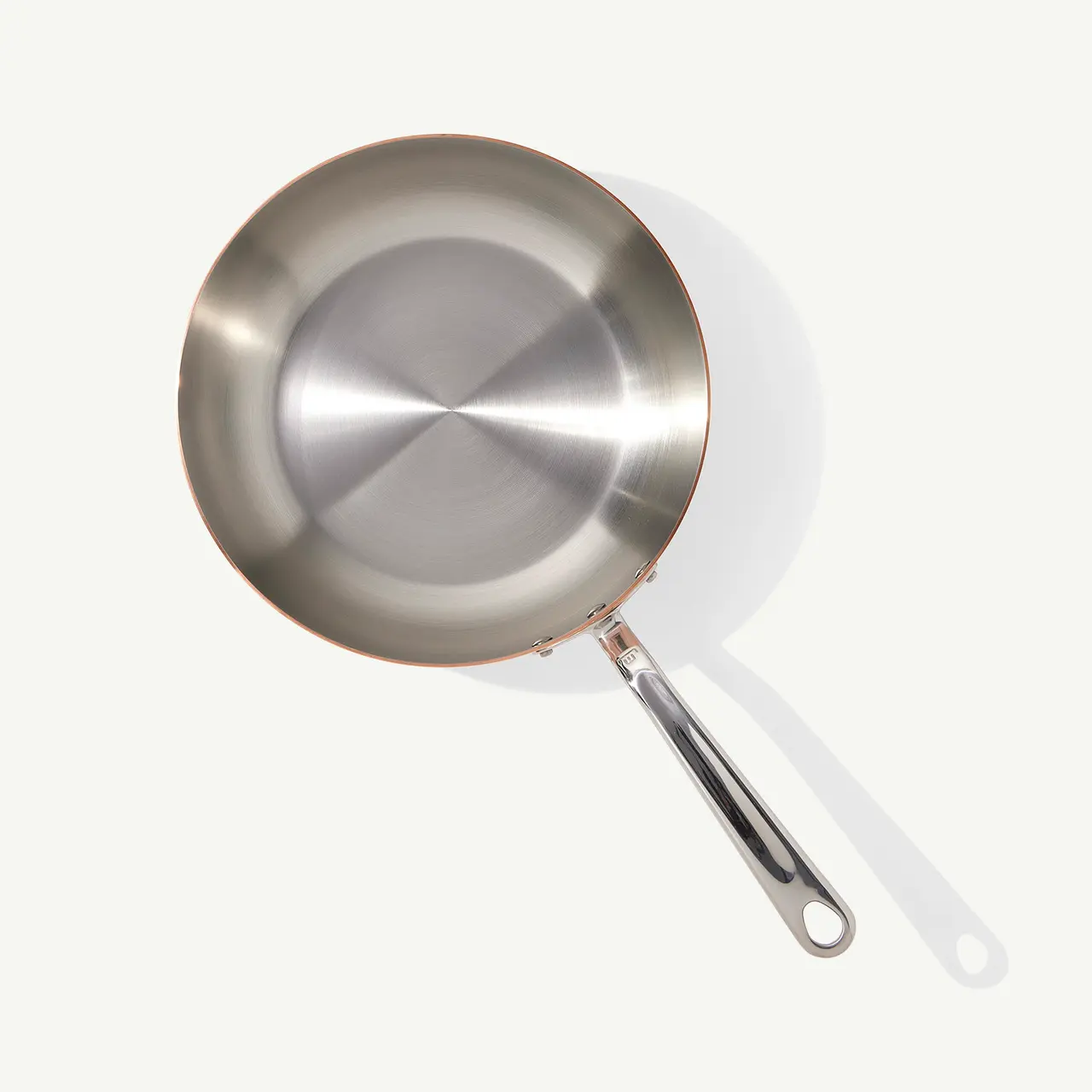 A stainless steel frying pan with a long handle is shown against a plain background, viewed from above.