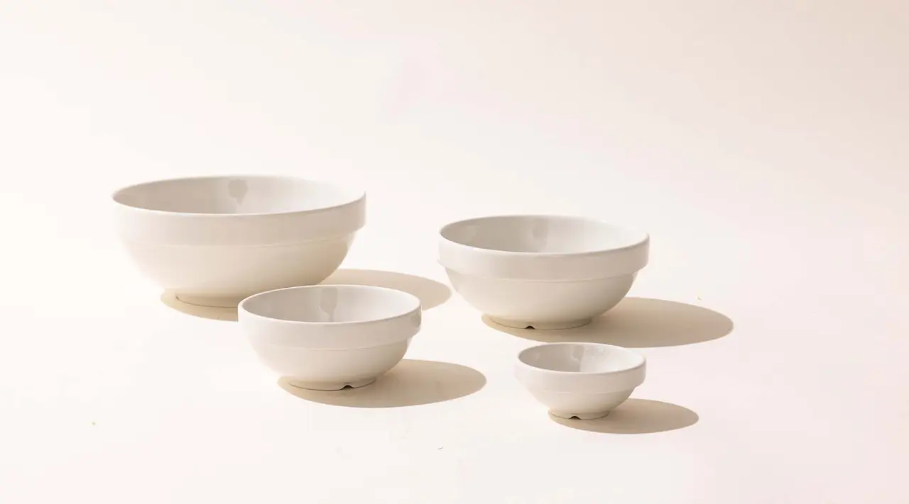 Four white bowls of progressively smaller sizes arranged from largest to smallest against a plain background.
