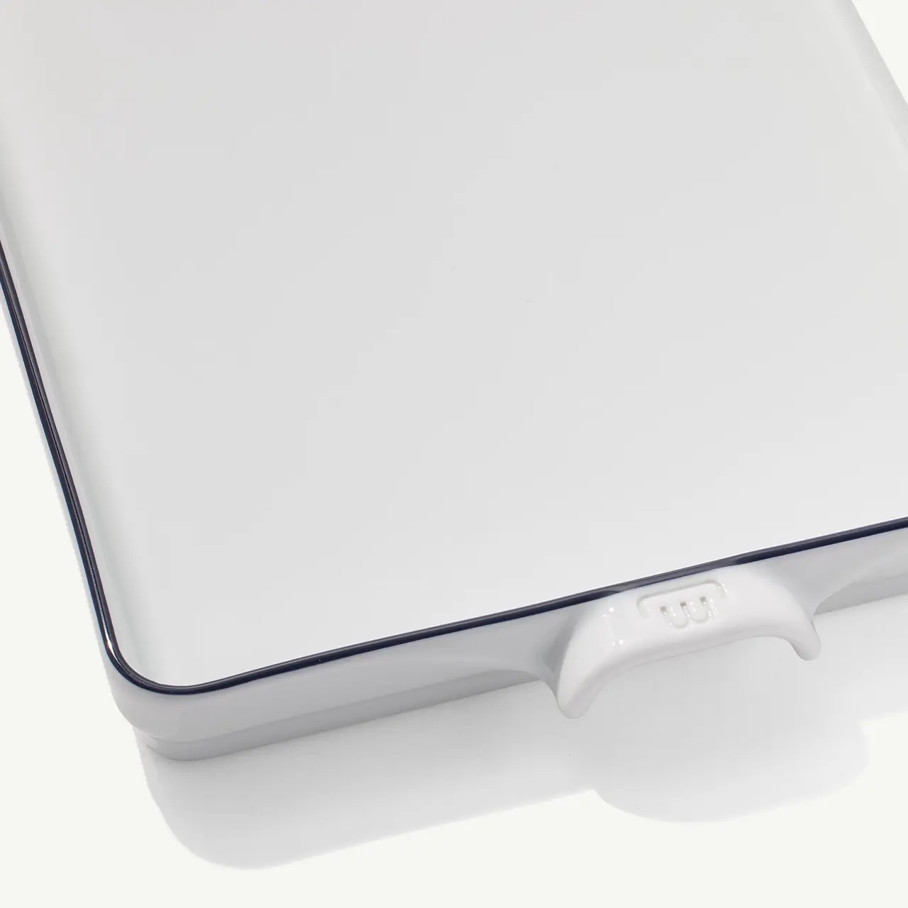 A close-up view of a white laptop corner with a distinctive blue edge and a small visible logo on its hinge against a white background.