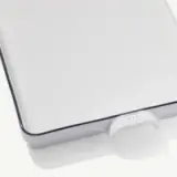 A close-up view of a white laptop corner with a distinctive blue edge and a small visible logo on its hinge against a white background.
