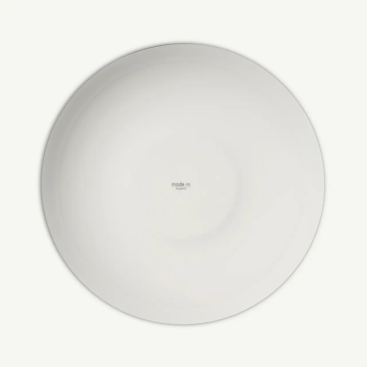 A plain white round plate with a text at the center that appears to be a brand name or logo.