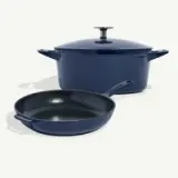 A blue cast iron skillet and a matching pot with a lid are placed on a light background.