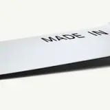 A close-up of a shiny metal surface displaying the phrase "MADE IN" in bold black letters.